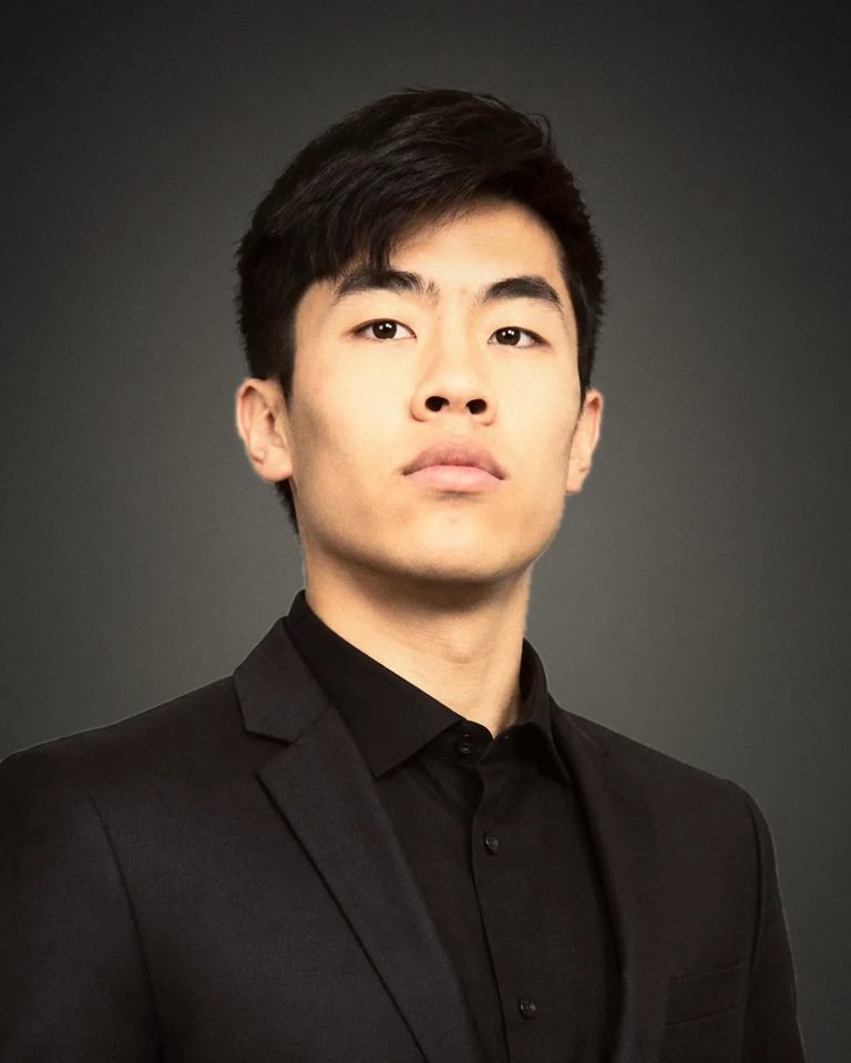 Evan Kwan, studio headshot in a black suit and shirt